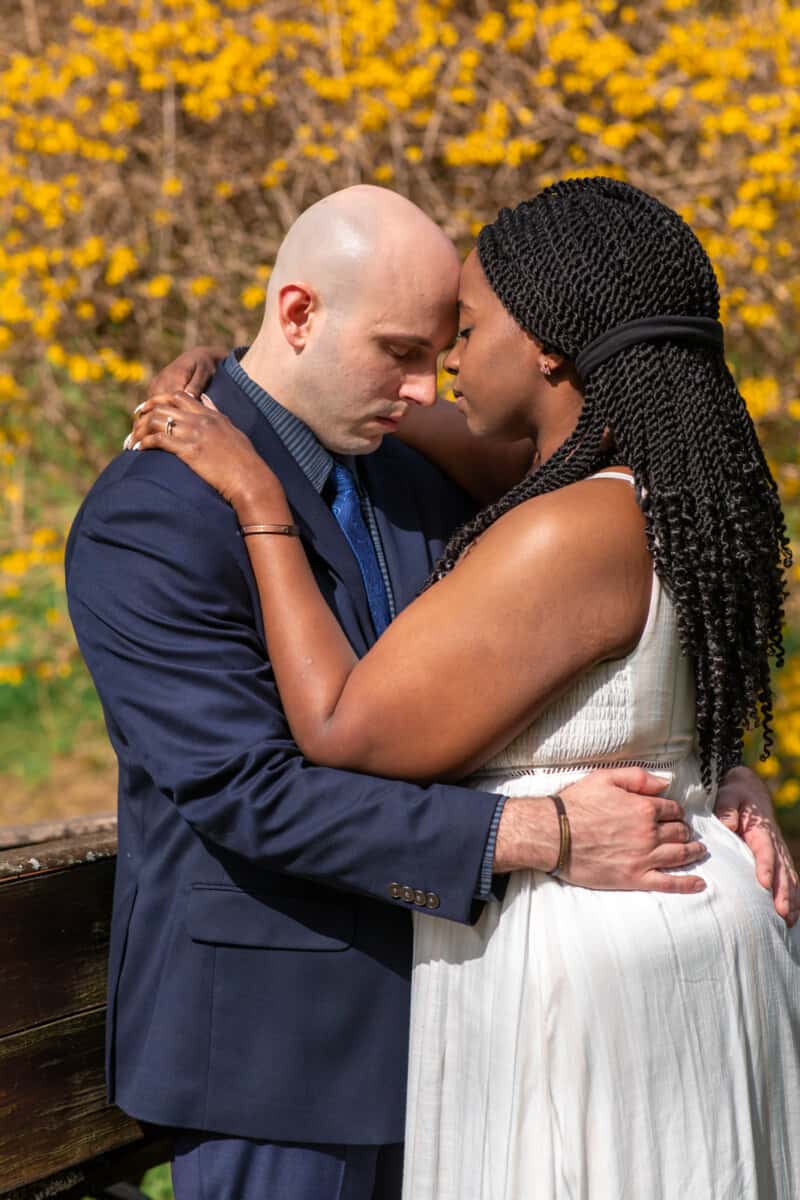 Spring Nashville Elopement at Butterfly Hollow; bride and groom with forheads touching in front of yellow flowered bush